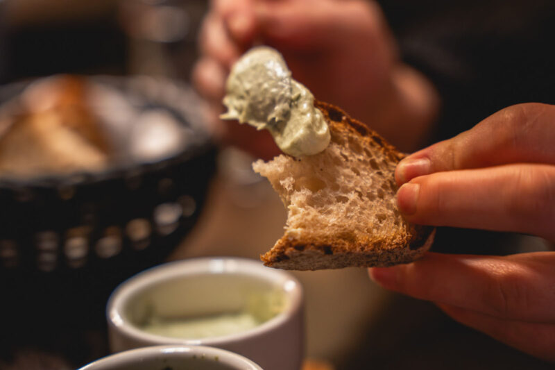 Frisch gebrochenes Sauerteigbrot mit Kräuterbutter, serviert mit einem Dip im Landhaus Begatal