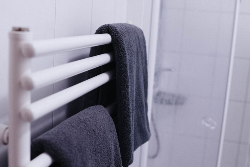 Beheizter Handtuchhalter mit anthrazitfarbenen Handtüchern im Badezimmer eines Hotelzimmers im Landhaus Begatal